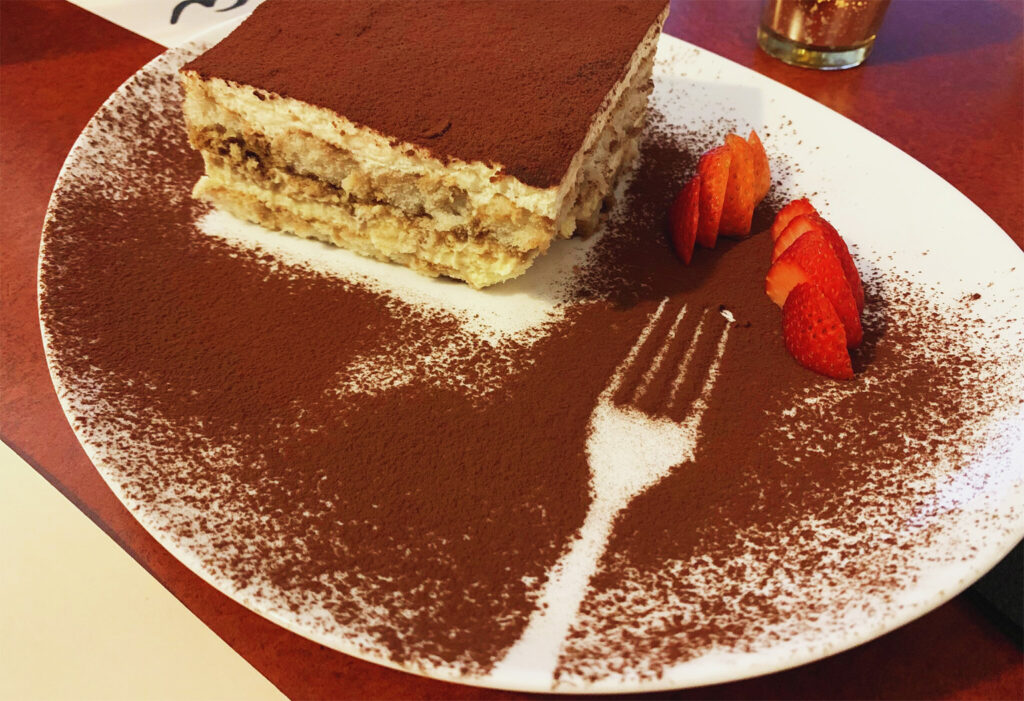 Lady finger tiramasu with a side of sliced strawberries.